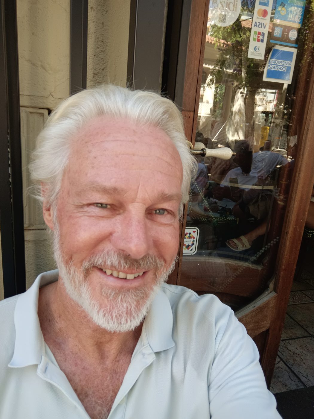 Hans smiling outside a café’s wooden doorway