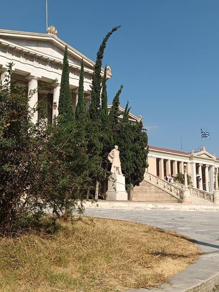 The neoclassical university building in Athens behind cypress trees