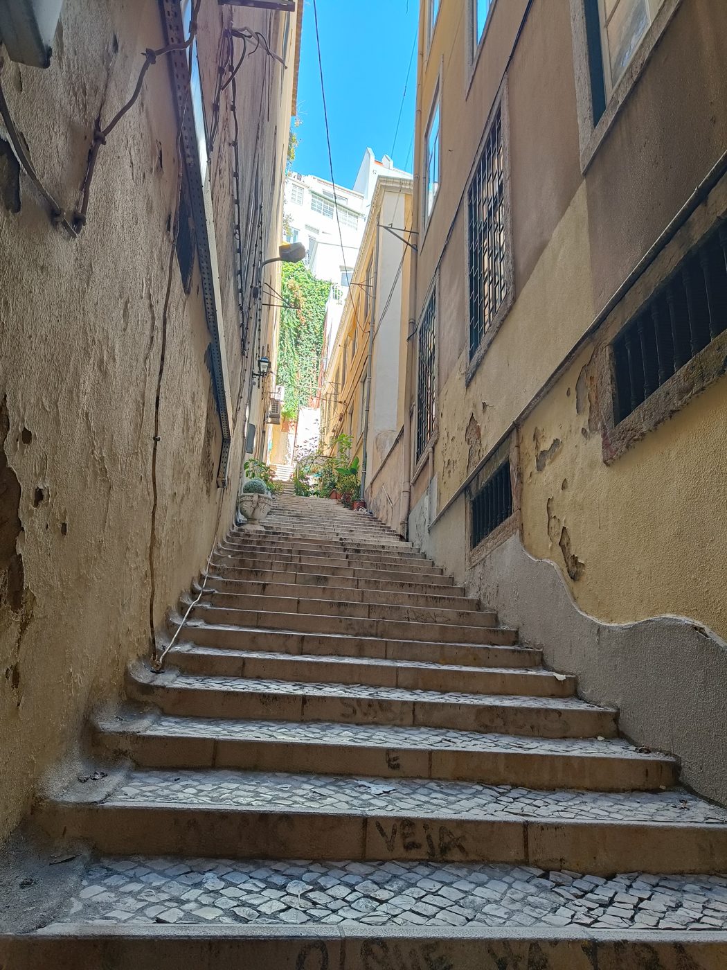 A narrow, steep stone stairway climbing between old buildings